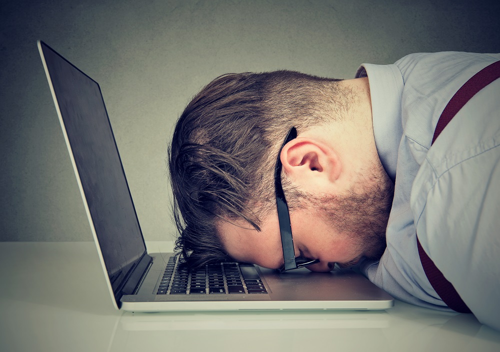 Frustrated man with head on laptop