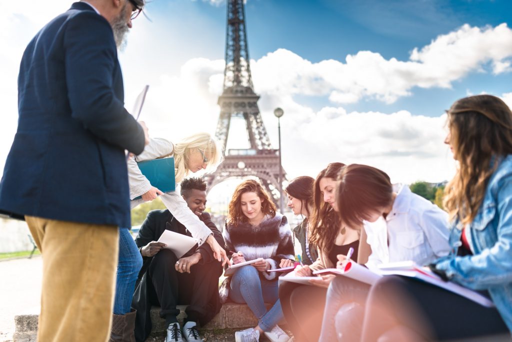 professor lectures students in front of the Eiffel Tower