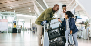 Father and mother waiting with young daughter at airport. Tourist family at airport terminal with luggage holiday.