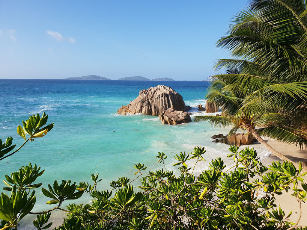 Seychelles beautiful tropical sandy beaches with the ocean and palm trees for Sky Bird Travel & Tours top travel destinations for 2023.