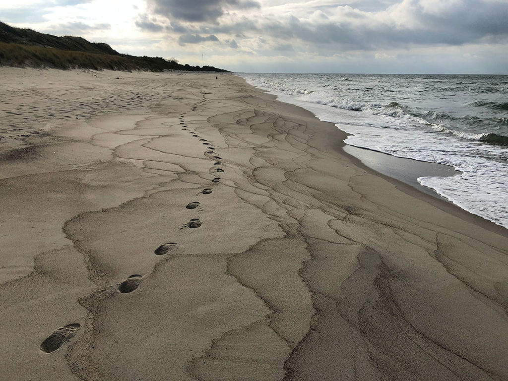 A stormy sky looms over the Baltic sea with the warm sand and waves in the Baltics for Sky Bird Travel & Tours top travel destinations in 2023.